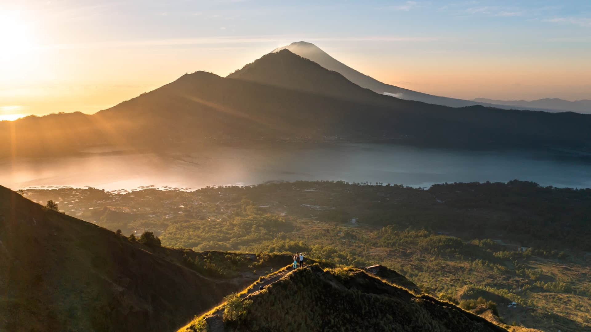 Drone capturing Mount Batur sunrise landscape with lava fields and volcanic textures.